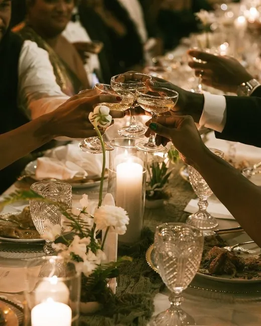 Guests raising coupes over a candlelit table