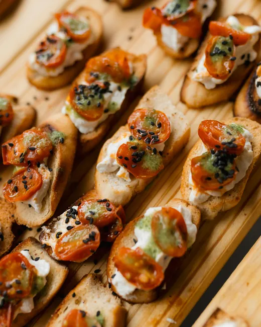 Rows of toasted crostini topped with roasted tomato and herbs