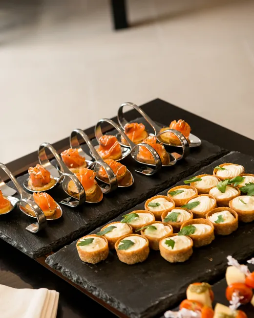 Canapé spoons and tartlets arranged on slate