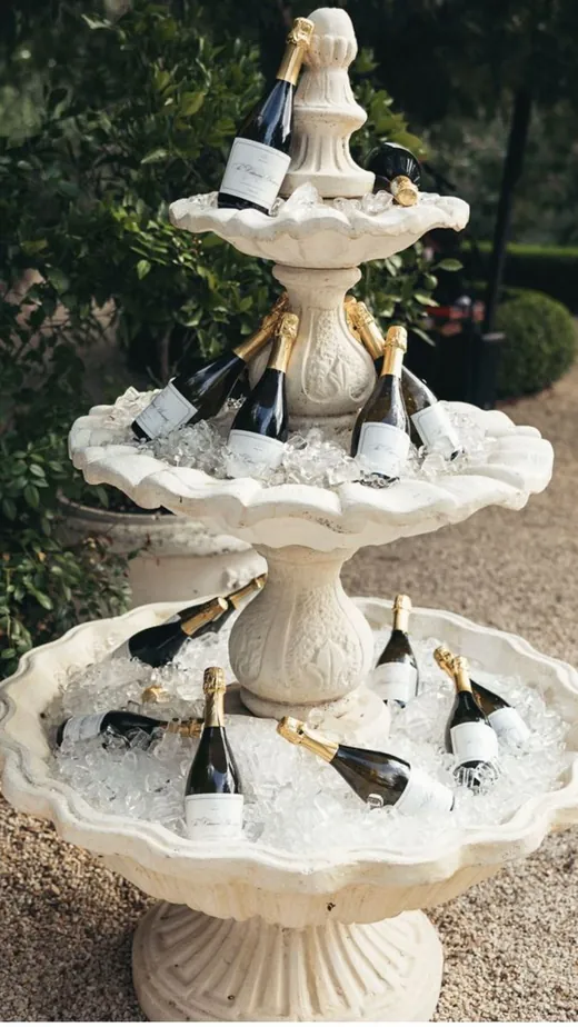 A tiered stone fountain filled with ice and bottles of champagne